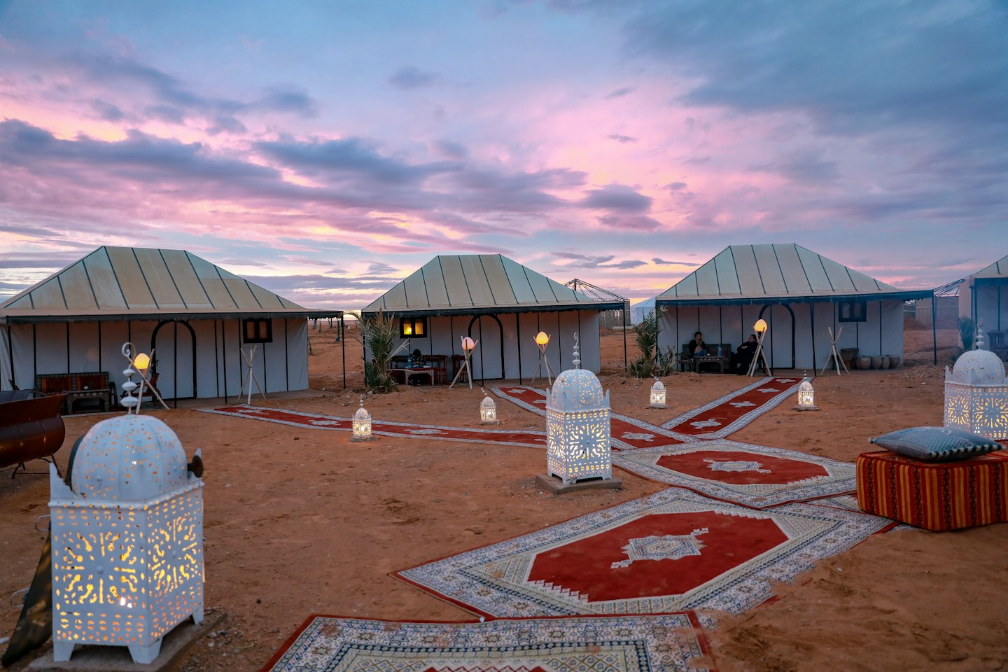 Luxury canvas tents with glowing lanterns on desert sand.