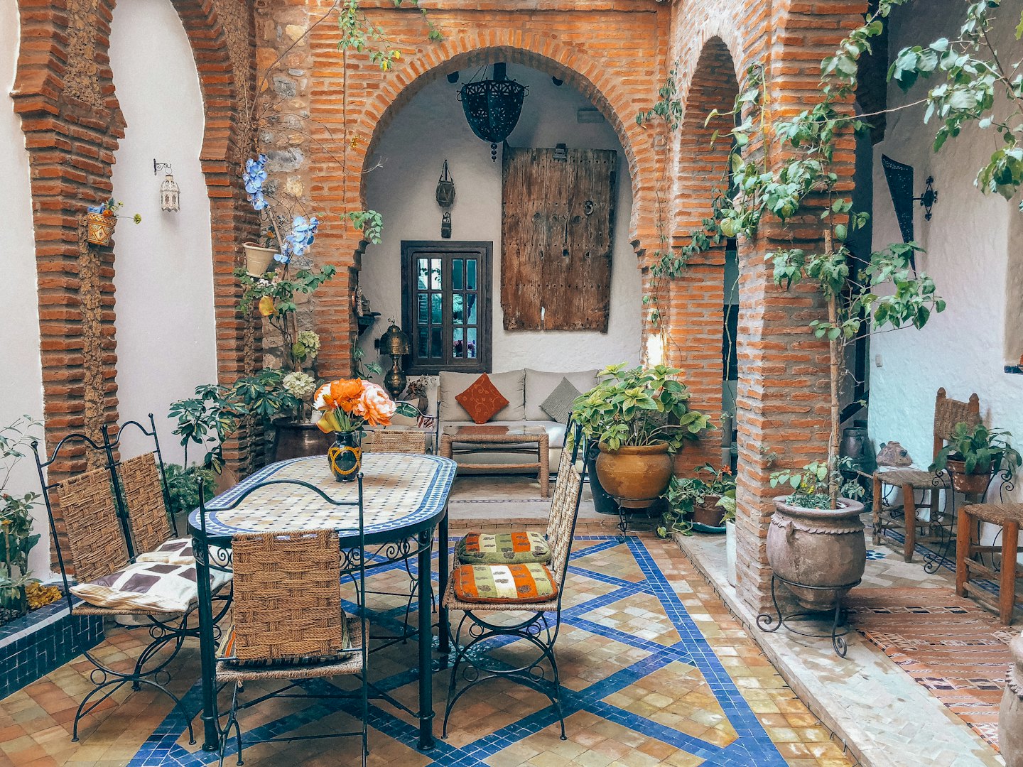 Courtyard with tiled floor, brick arches, plants, and seating.